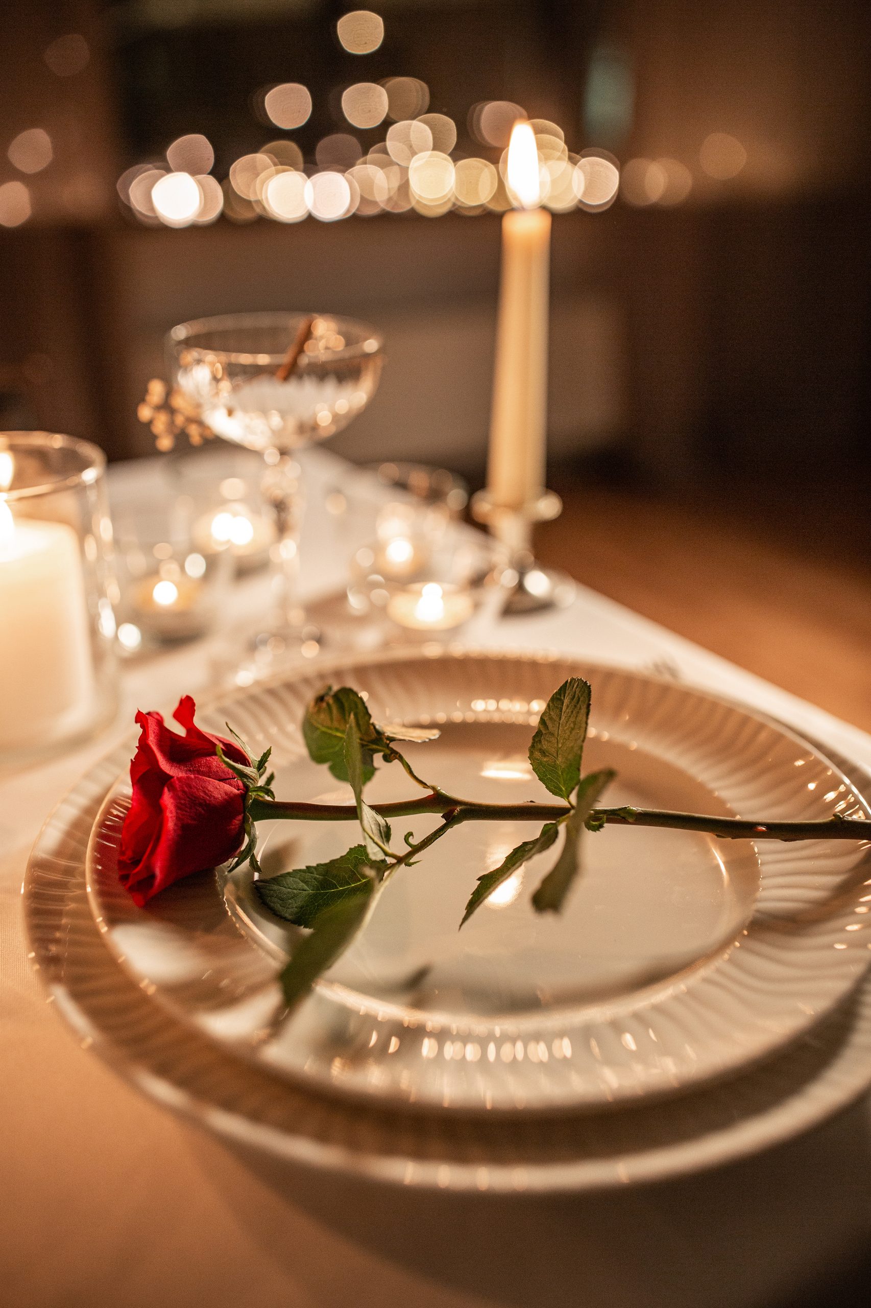 Romantisch gedeckter Tisch mit roter Rose auf dem Teller, Kerzenlicht und Gläsern, Detail im Restaurant der Churfürstlichen Waldschänke Moritzburg