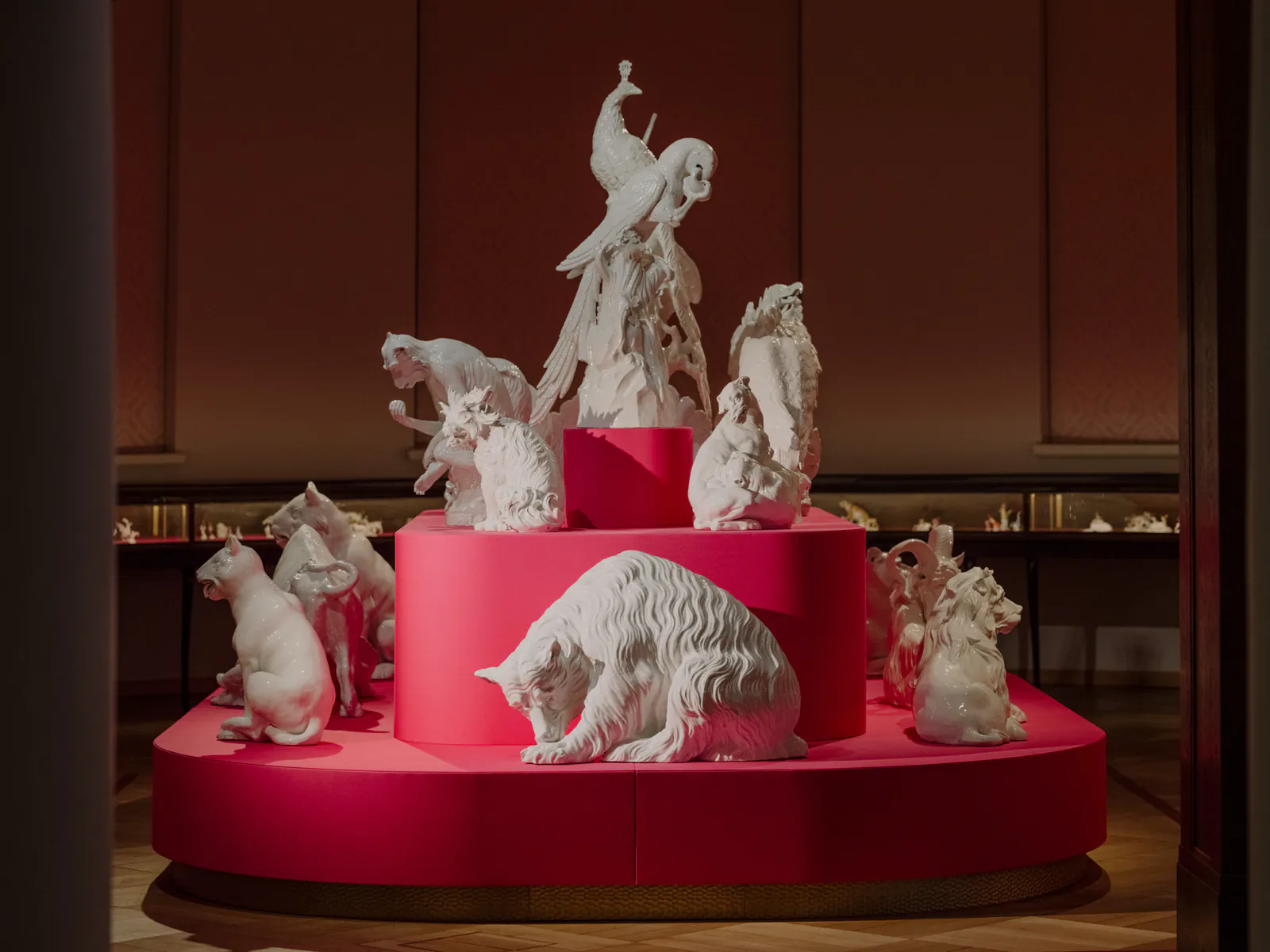 meissen_museum_tier-pyramide Weiße Porzellantiere, darunter Papagei und Katzen, auf einem pinkfarbenen Podest im MEISSEN Museum